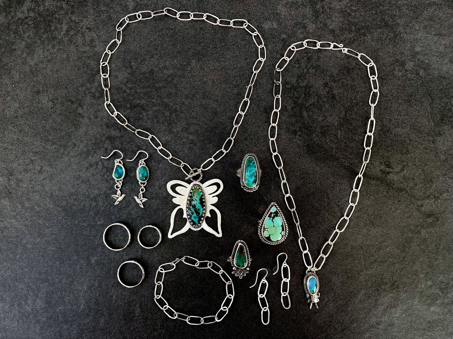 Sterling Silver pieces of jewelry featuring turquoise stones and handmade chains on a dark background